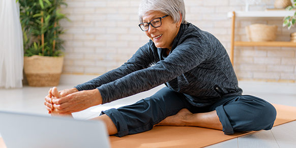 Woman on yoga mat with computer
