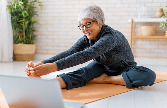Woman on yoga mat with computer